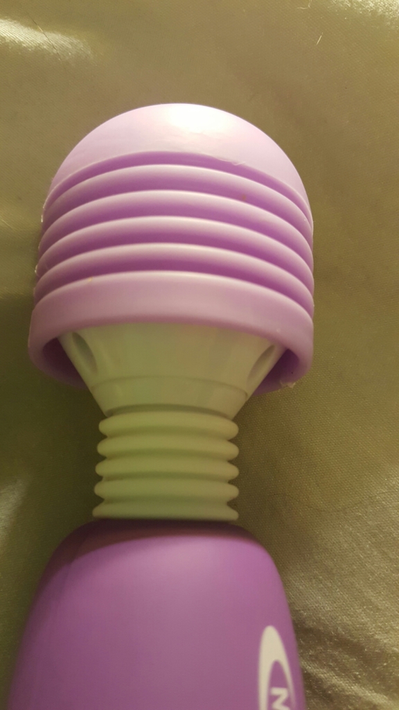 A close up of the ridged head of the purple mighty wand vibrator. An accordion-like stem neck is visible below the purple mushroom-like cap.